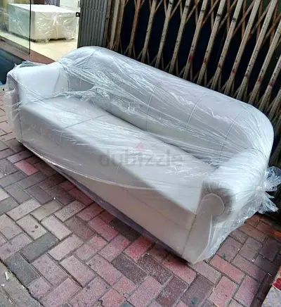 Two-seater white leather sofa wrapped in plastic - good condition