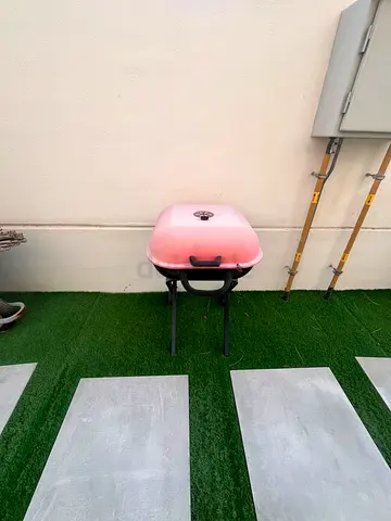 Portable pink outdoor charcoal grill with foldable legs