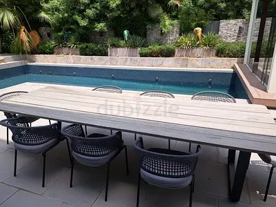 Outdoor dining table with 6 woven chairs by pool