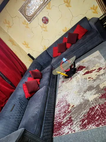 Large L-shaped Grey Sofa with Red Cushions and Matching Rug