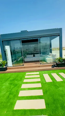 Glass-enclosed outdoor lounge pod with sofa on rooftop garden