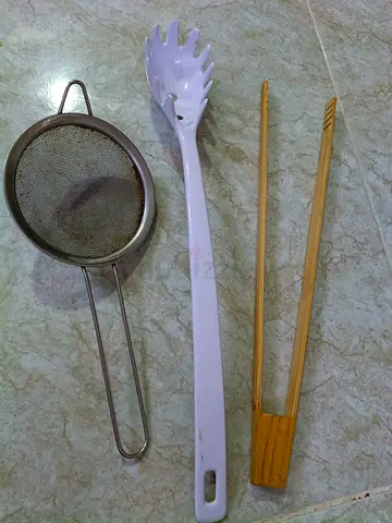 Set of kitchen serving utensils: pasta server, strainer and tongs