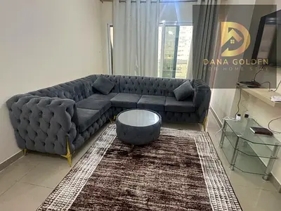 One-bedroom apartment with living room, bathroom, and balcony, furnished with hotel-style furniture, available in Sharjah Al Taawun.