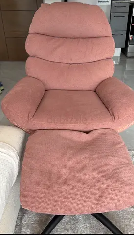 Comfortable pink upholstered reclining armchair with ottoman