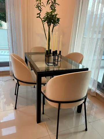 Modern Crate  Barrel dining table with a black metal frame and glass top, measuring 122 cm (L) × 71