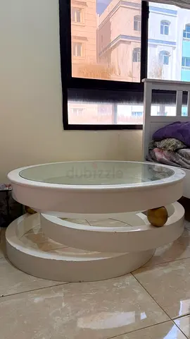 Round white glass-top coffee table with gold accents