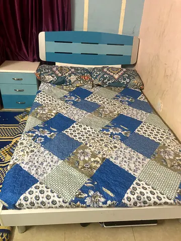 Queen bed with blue headboard. Side table and Study table with shelf.