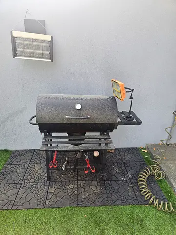 Used outdoor charcoal grill with side shelf and tool hooks