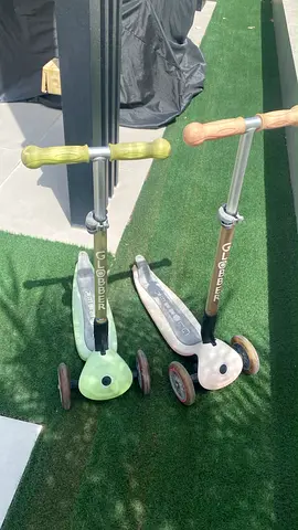 Pair of pink and green Globber three-wheel kids scooters - good used condition