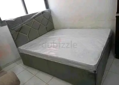Grey upholstered bed with patterned headboard and mattress