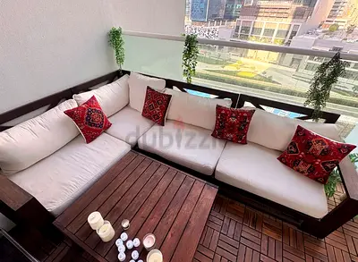 Outdoor wooden L-shaped sofa set with white cushions and coffee table