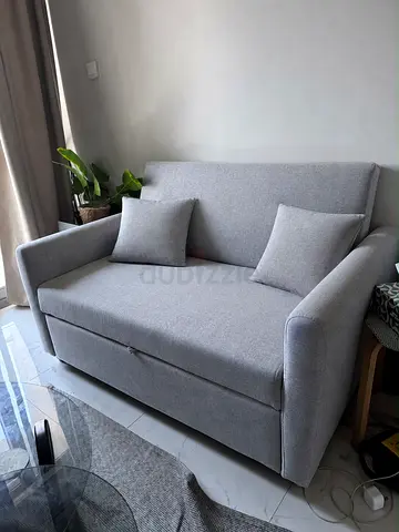 Light grey two-seater sofa bed in good condition