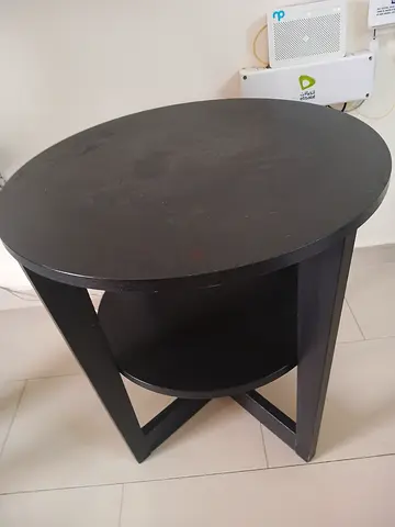 Black round wooden side table with lower shelf