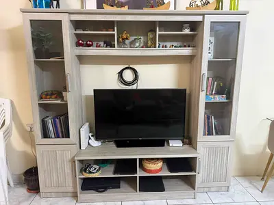 Light wood entertainment center with glass cabinets and shelving