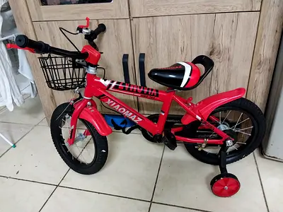 Red kids bicycle with training wheels and front basket