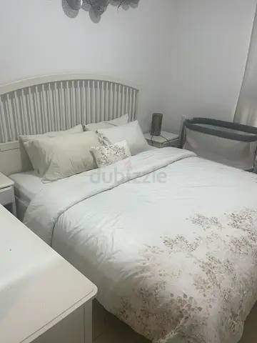 Queen size white upholstered bed with headboard and bedding