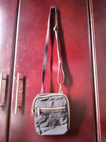 Compact black crossbody shoulder bag with front zip pocket