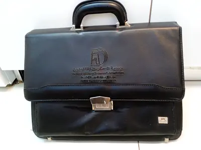 Black leather briefcase with embossed logo, used, good condition