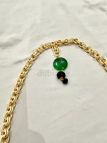 Gold-tone chain necklace with green jade-like pendant and black bead charm