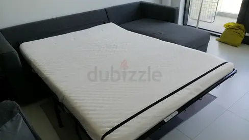 Grey L-shaped sofa with pull-out bed and mattress