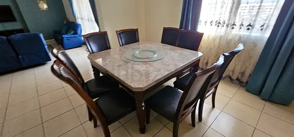 Solid wood 8-seater dining table with marble top - good condition with revolving lazy susan.