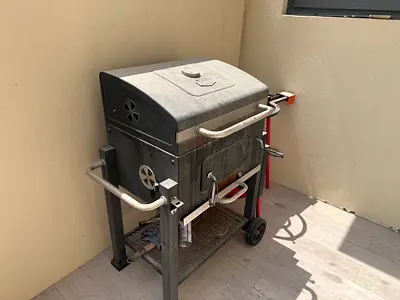 Used charcoal BBQ grill with side handles and wheels - needs cleaning