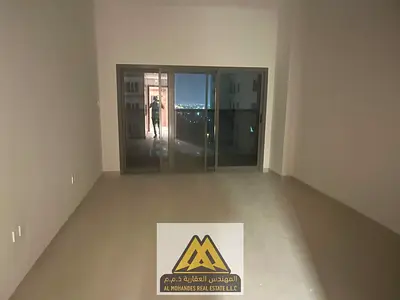 Large studio for annual rent in Azha Garden Residence, Al Amerah Ajman. Spacious area, balcony, central AC, built-in wardrobes, equipped kitchen, free