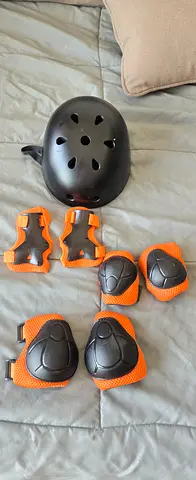 Kids black helmet with orange knee and elbow pads set - good condition