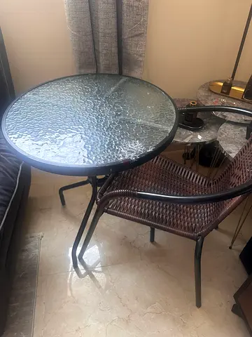 Round glass-top bistro table with two rattan chairs