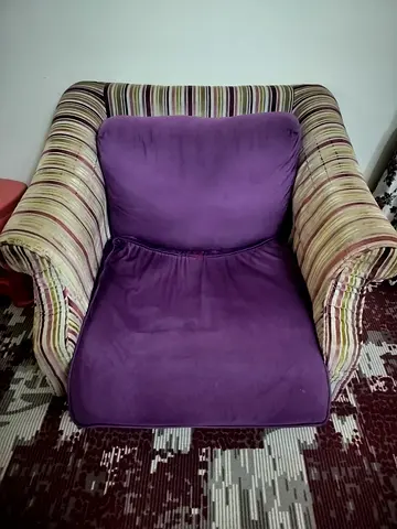 Comfortable single armchair with purple cushions and striped arms