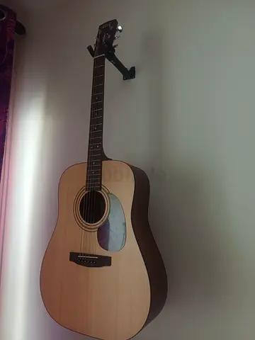 Acoustic guitar in good condition, hangs on wall mount
