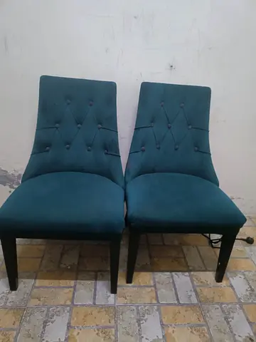 Pair of teal upholstered dining chairs with button tufting