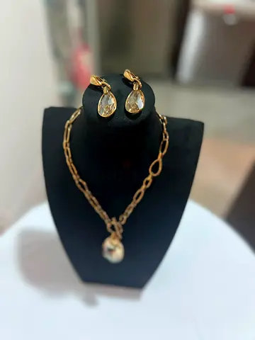 Gold-tone chain necklace with teardrop crystal pendant and matching earrings