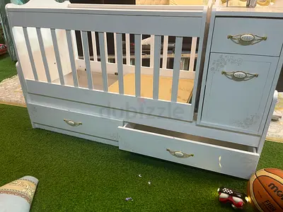 White convertible baby crib with attached drawers and changing unit