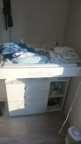 White nursery changing table with storage drawers and shelves