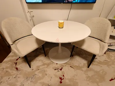 Round white tulip dining table with two upholstered boucle chairs