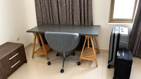 IKEA-style trestle desk with swivel office chair — light wood dark top
