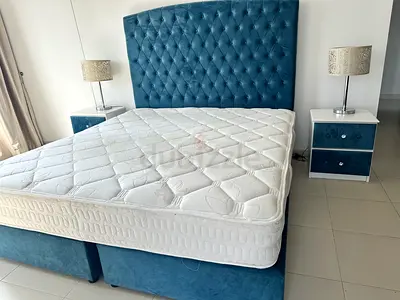 Blue upholstered bed frame with mattress and matching nightstands