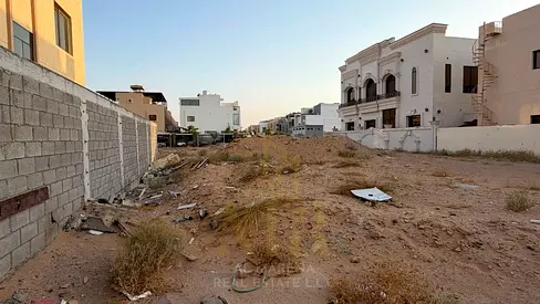 Residential land for sale in Al Alia, Ajman, measuring 4,350 sq ft, located on a street and alley, with a building permit for a ground floor + two flo
