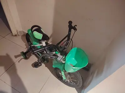 Green kids bicycle with training wheels and front basket