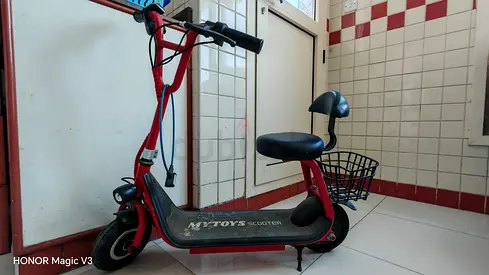 Red electric sit-down scooter with basket for kids.