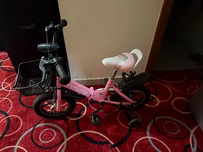 Pink kids bicycle with training wheels and front basket - good condition