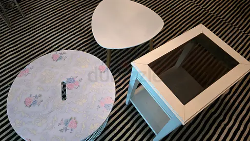 Set of small white side tables and glass-top coffee table on striped rug