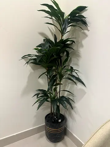Tall artificial indoor potted plant — green foliage in decorative pot