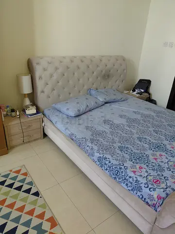Beige tufted queen bed with mattress and bedside table