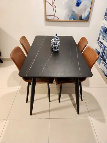 Modern black marble-top dining table with 4 brown chairs