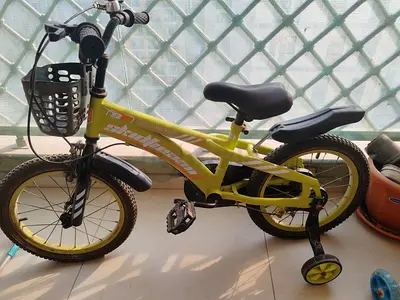 Yellow kids bicycle with training wheels and front basket - good condition