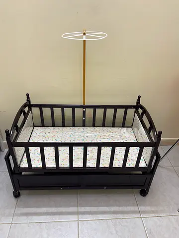 Dark wooden baby crib with storage drawer and mattress - good condition