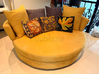 Single mustard yellow curved lounge chair with pillow