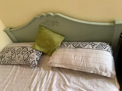 Pastel green wooden queen size bed with decorative headboard
